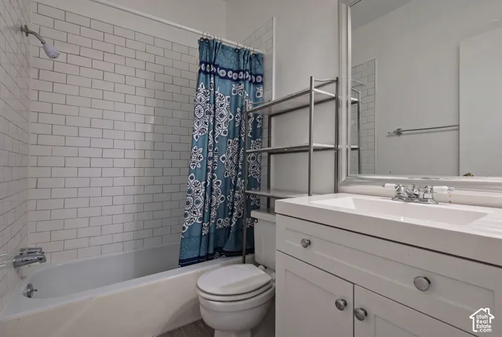 White subway tile shower surround, shower/tub combination, white vanity with integrated sink, chrome faucet, and framed mirror