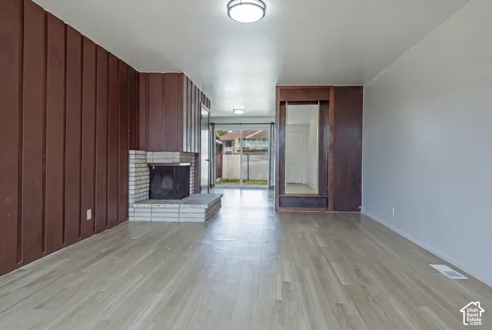 Living area featuring wood-finish flooring, a brick fireplace, a wood-paneled accent wall, and a built-in storage niche