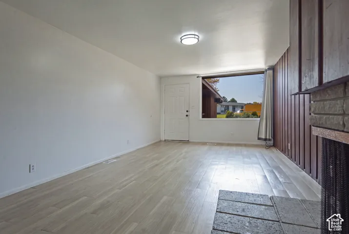 Wood-finish flooring with a stone hearth and a wood-paneled accent wall