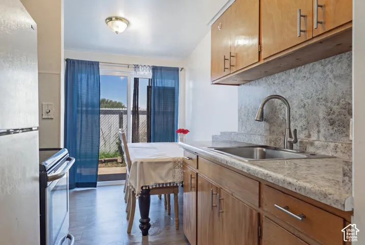 Kitchen featuring wood cabinetry, stainless steel sink, pull-down faucet, and light-toned countertops