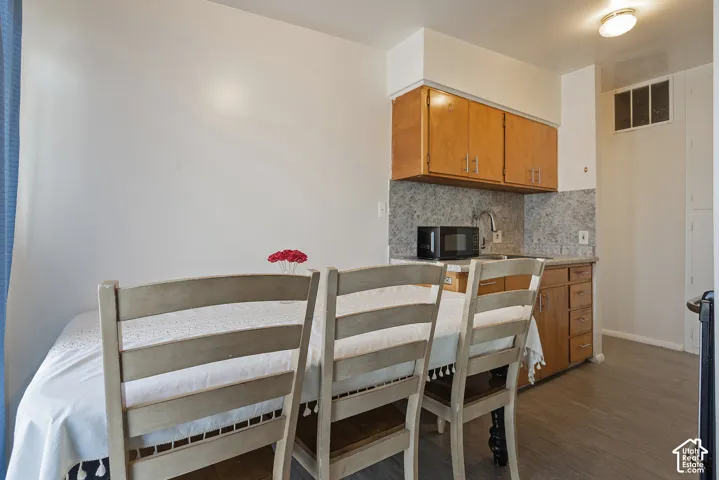 Kitchenette with wood-finish cabinetry, a stainless steel sink, and a microwave