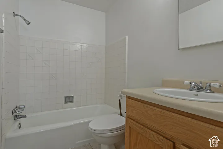 Bathroom featuring a vanity with an integrated sink, a built-in bathtub with shower, and white wall tile