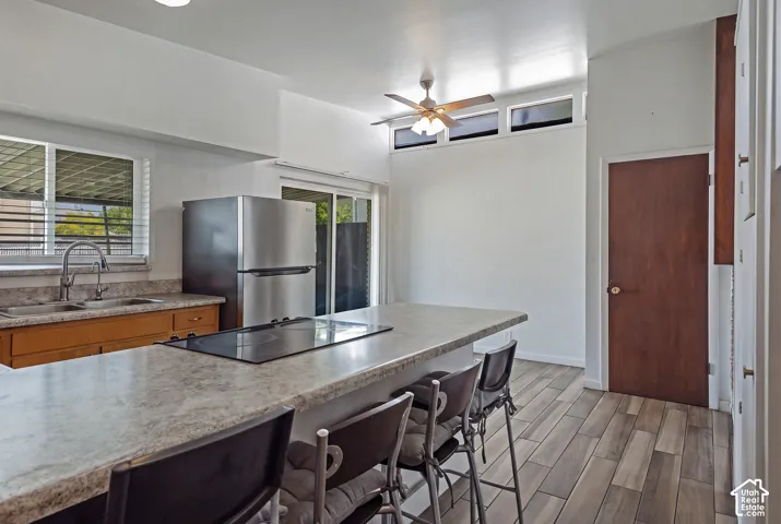 Kitchen featuring a stainless steel refrigerator, built-in cooktop, and wood-finish flooring