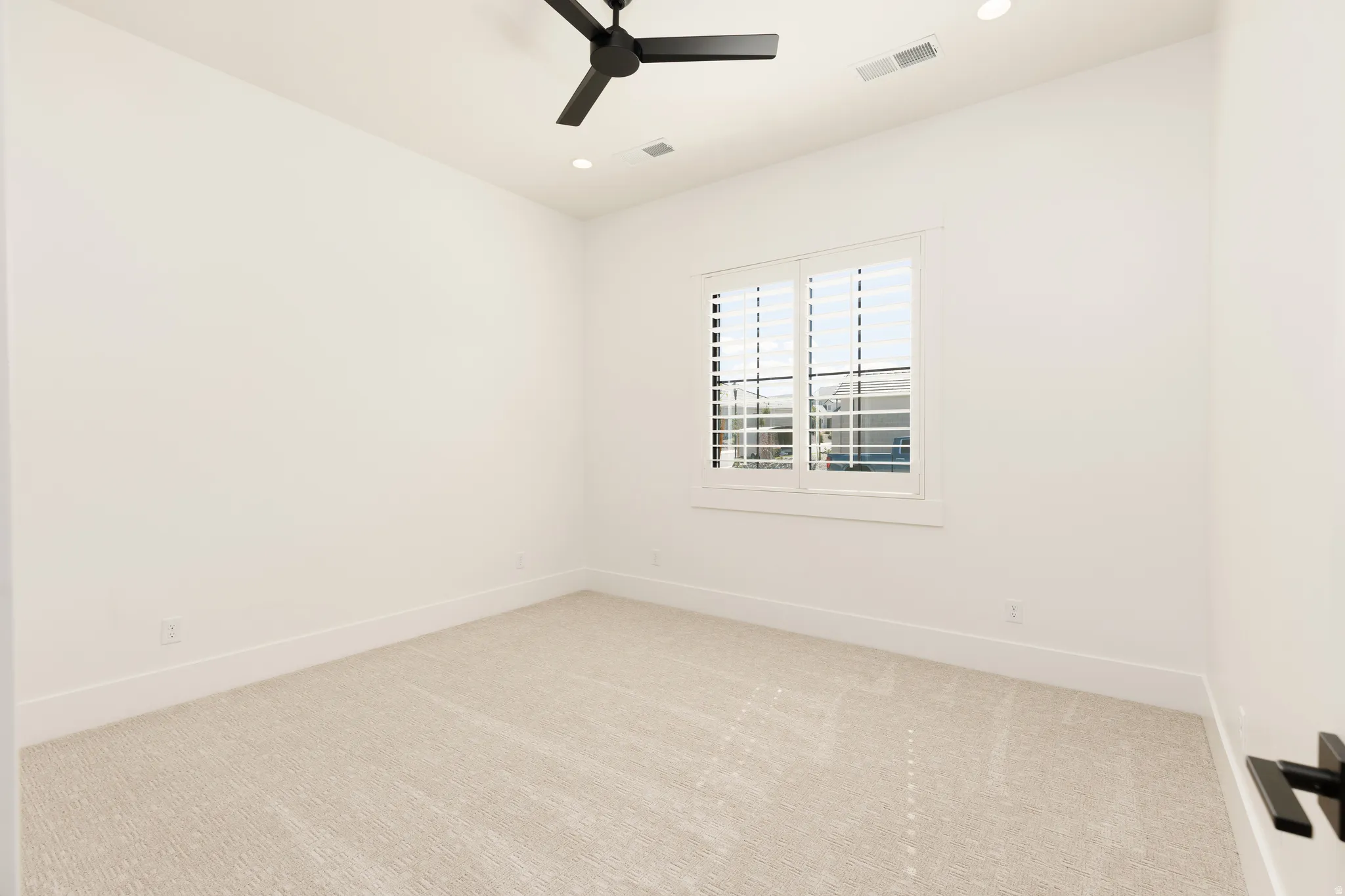 Recessed lighting, black ceiling fan, plantation shutters, light-toned carpeting, and white walls