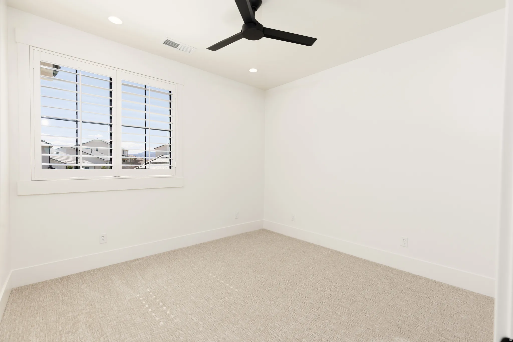 Recessed lighting, ceiling fan, window with plantation shutters, light-toned carpeting, and white walls