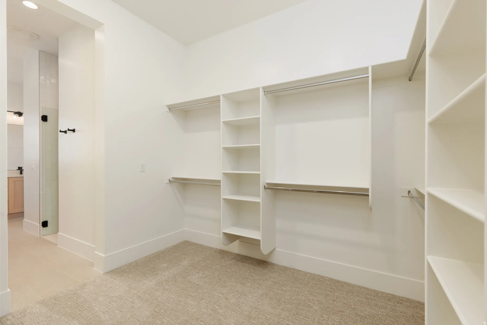 Walk-in closet featuring built-in shelving, multiple hanging rods, and neutral-toned carpeting