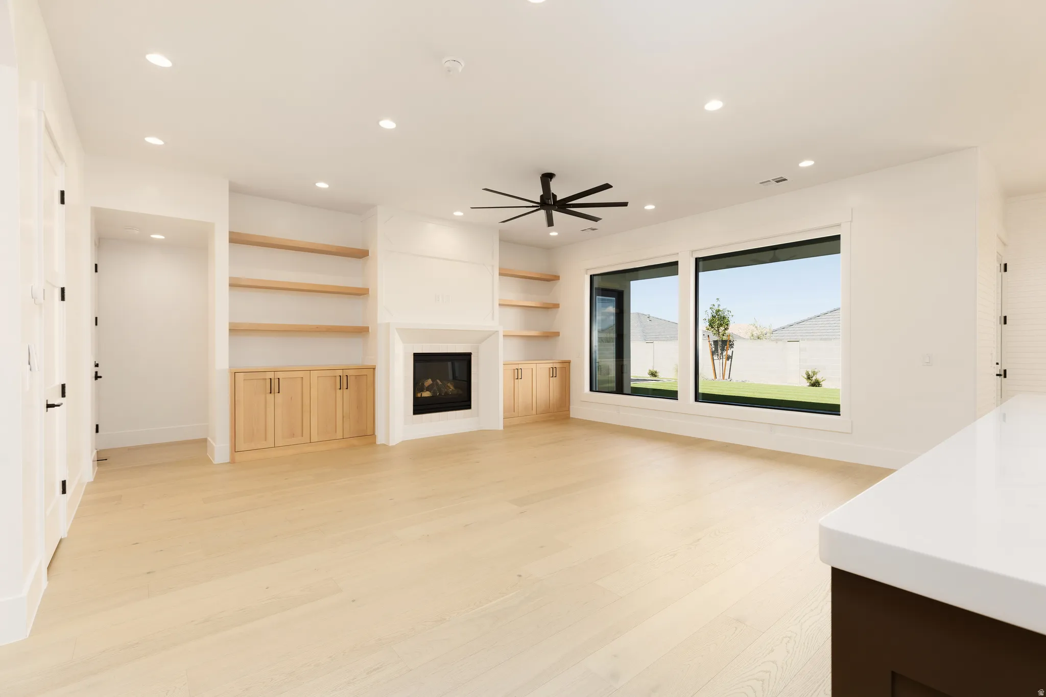Recessed lighting, wood-finish flooring, built-in shelving with cabinetry, modern fireplace, and large windows