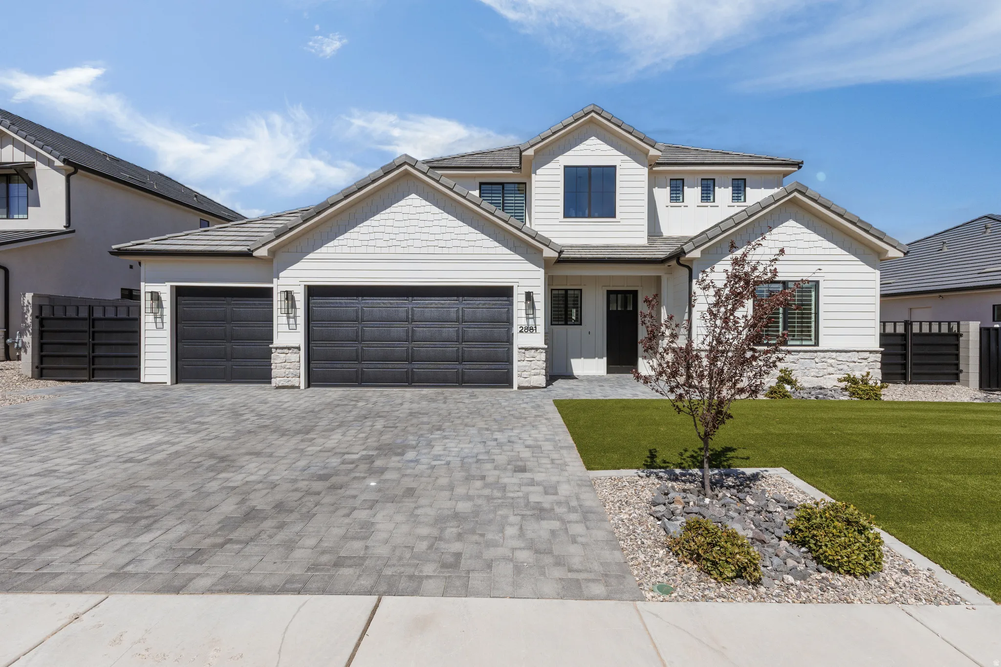 Contemporary facade with white siding, stone accents, and a dark tile roof