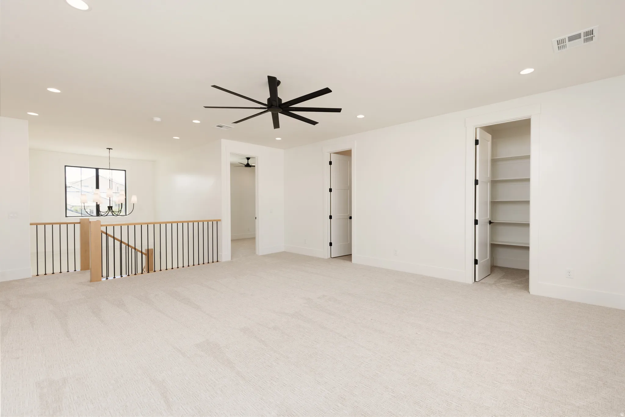Spacious carpeted area featuring a contemporary ceiling fan, recessed lighting, and a built-in storage closet with shelving