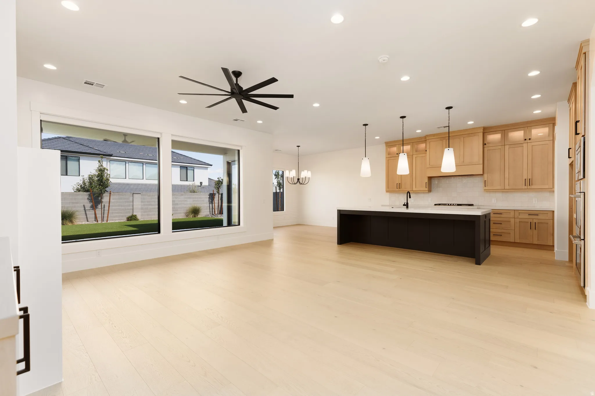 Open-concept living space with light wood-finish flooring, recessed lighting, and a contemporary ceiling fan
