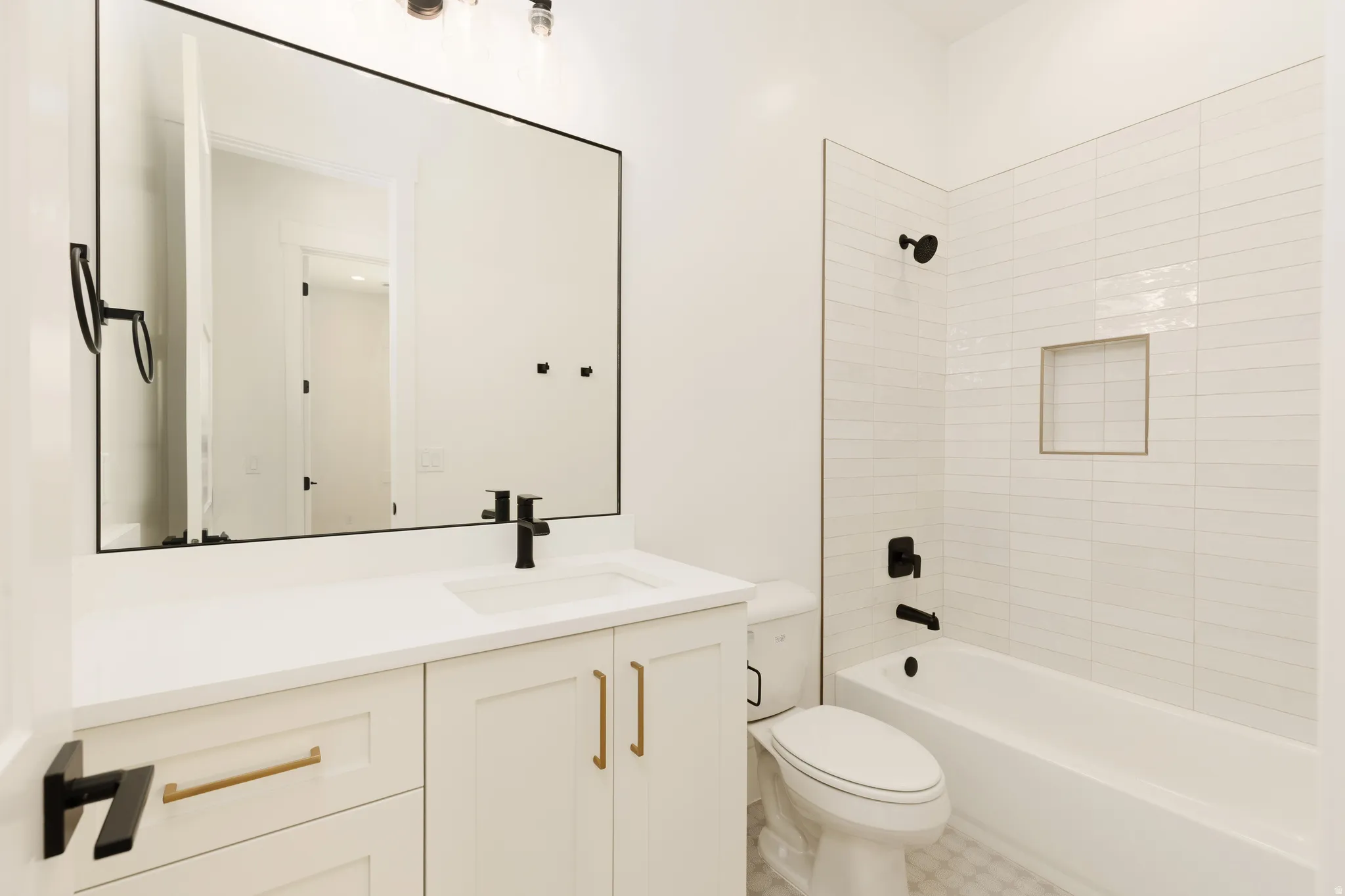 Contemporary bathroom featuring a white vanity with gold-tone hardware, rectangular undermount sink, and a black-framed mirror