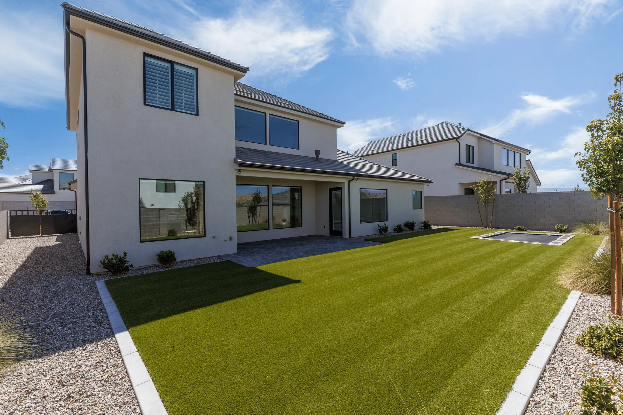 Expansive rear yard featuring artificial turf, a built-in trampoline, and a gravel border