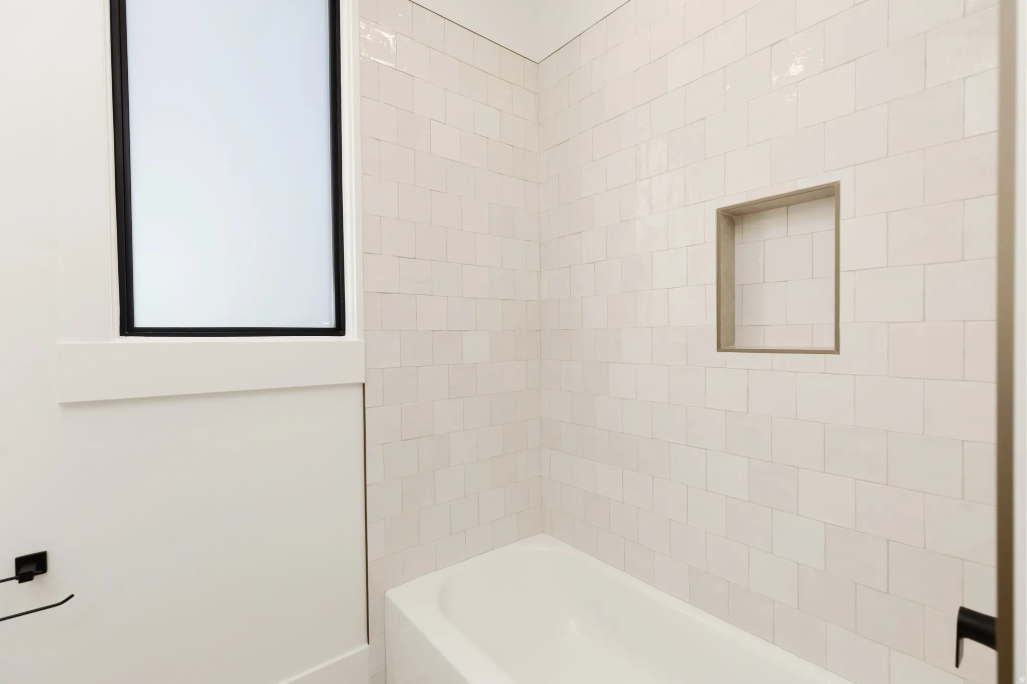 Integrated bathtub with a tiled surround featuring a recessed niche