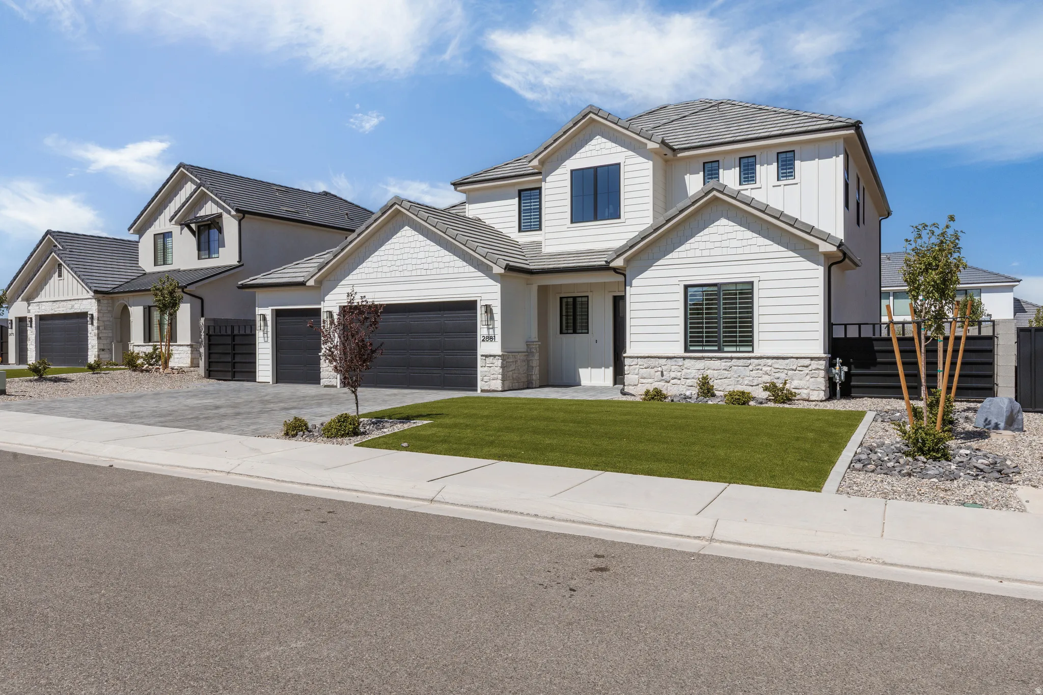 Contemporary exterior featuring board and batten siding, stone accents, dark-framed windows, and a paver driveway