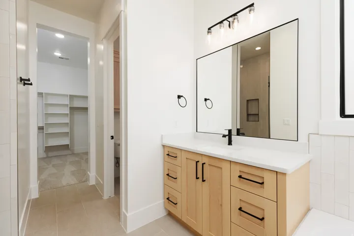 Vanity with light wood-finish cabinetry, white countertop, and matte black hardware