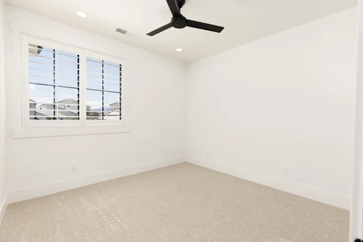 Recessed lighting, ceiling fan, window with plantation shutters, light-toned carpeting, and white walls