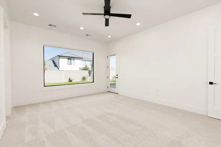 Recessed lighting, ceiling fan, expansive window, white walls, and light-toned carpeting