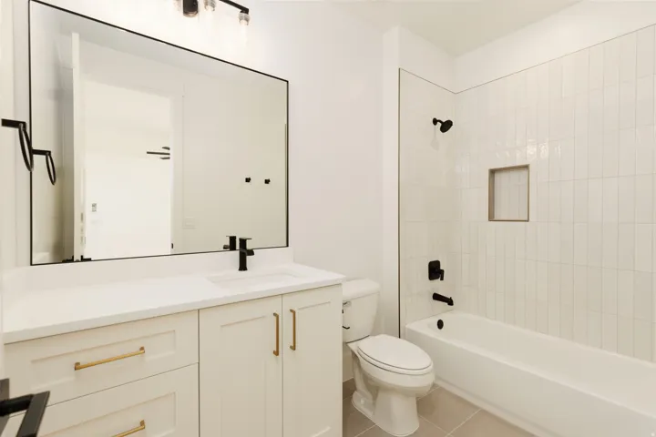 Bathroom featuring a white vanity with gold-tone hardware, rectangular sink, and black faucet