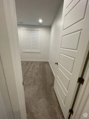 Recessed lighting, white plantation shutters, white paneled door, and carpeted flooring