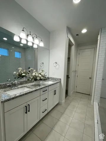 Double vanity with granite countertop, dual undermount sinks, and white cabinetry with matte black hardware