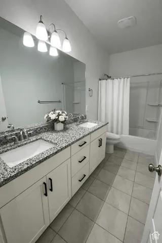 Dual vanity with granite-style countertop, white cabinetry with matte black hardware, and an integrated tub-shower combination