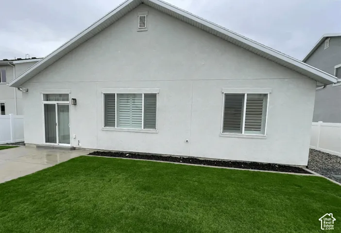 White stucco exterior featuring a sliding glass door, white framed windows, and a manicured lawn