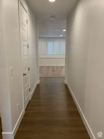 Wood-finish flooring leading to a carpeted room with white plantation shutters