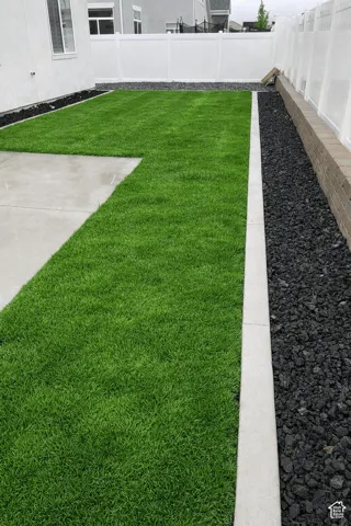 Manicured lawn with concrete patio, gravel landscaping, and privacy fencing