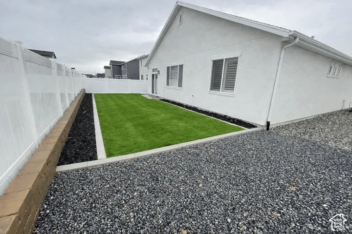 Artificial turf lawn bordered by black mulch and a concrete curb