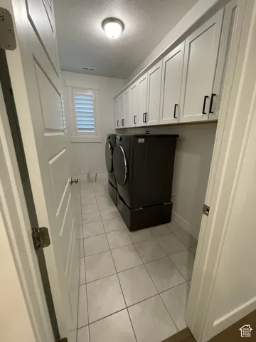 White shaker-style cabinetry with black hardware, tiled flooring, plantation shutters, and a flush mount ceiling light fixture