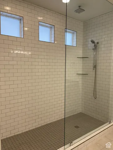 Walk-in shower with subway tile walls, tile flooring, glass enclosure, and integrated shelving