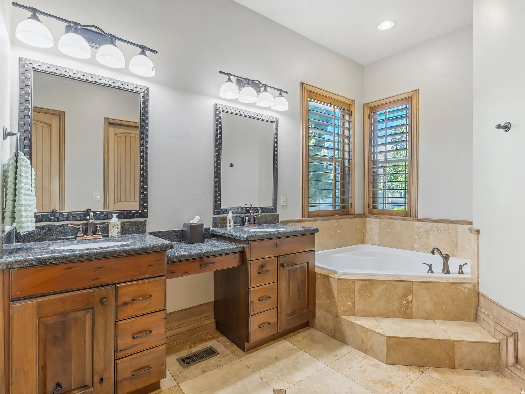 Dual wood-finish vanities with dark granite countertops and integrated sinks
