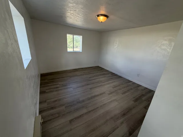Wood-finish flooring throughout, with a window providing natural illumination, and a ceiling-mounted light fixture