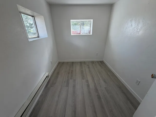 Wood-finish flooring, white painted walls, and two windows