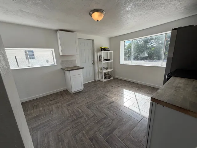 Wood-finish herringbone tile flooring, white shaker-style cabinetry, and a subway tile backsplash