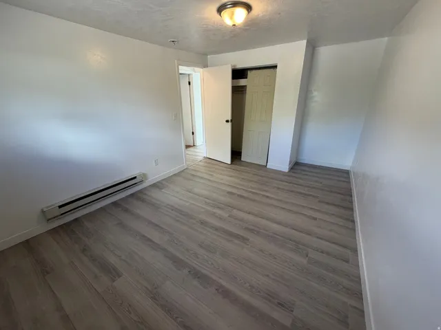 Wood-finish flooring throughout, white painted walls, and a built-in closet with bi-fold doors