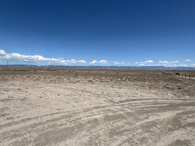 Expansive undeveloped land featuring a dirt road and distant mountain range