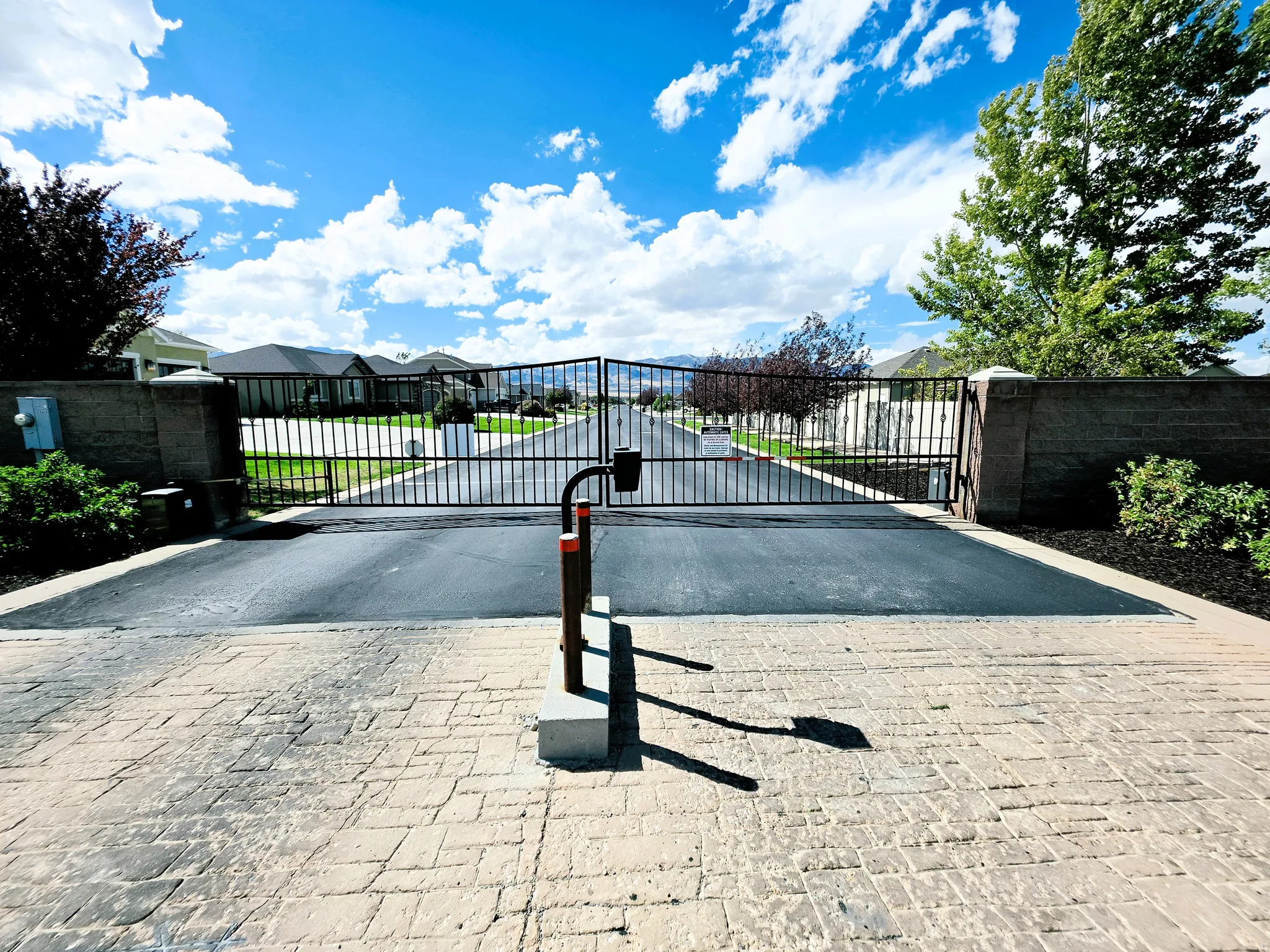 Gated entry featuring a stamped paver driveway and an asphalt approach