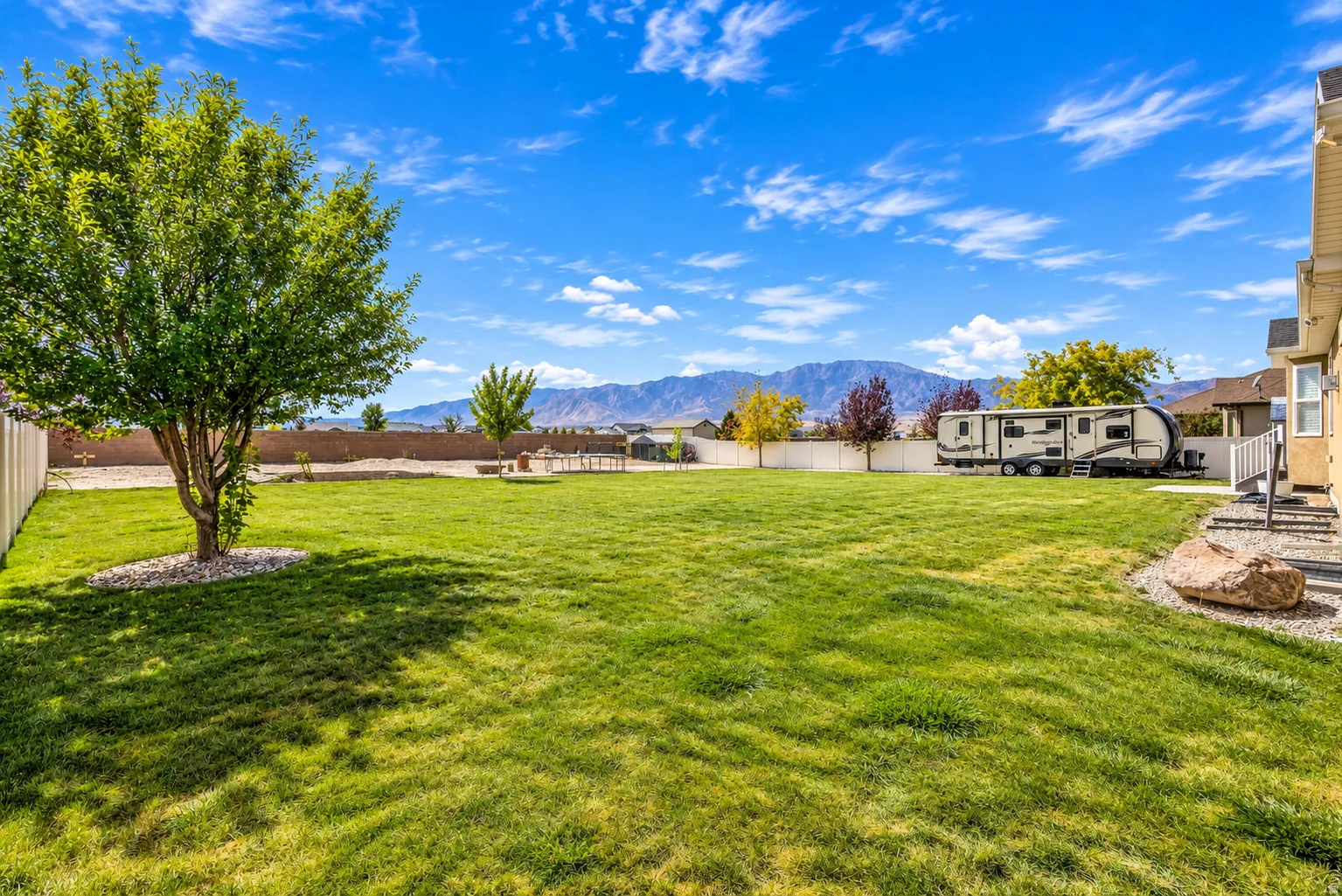 Expansive backyard featuring a lush lawn, mature trees, and a privacy fence
