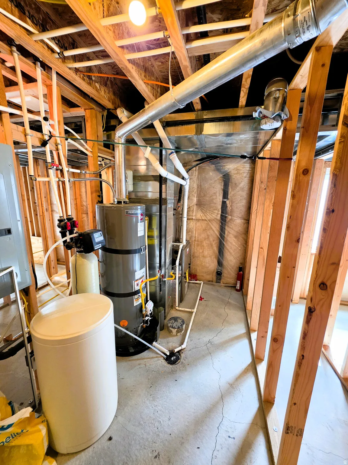 Utility area featuring exposed wood framing, water heater, water softener and furnace