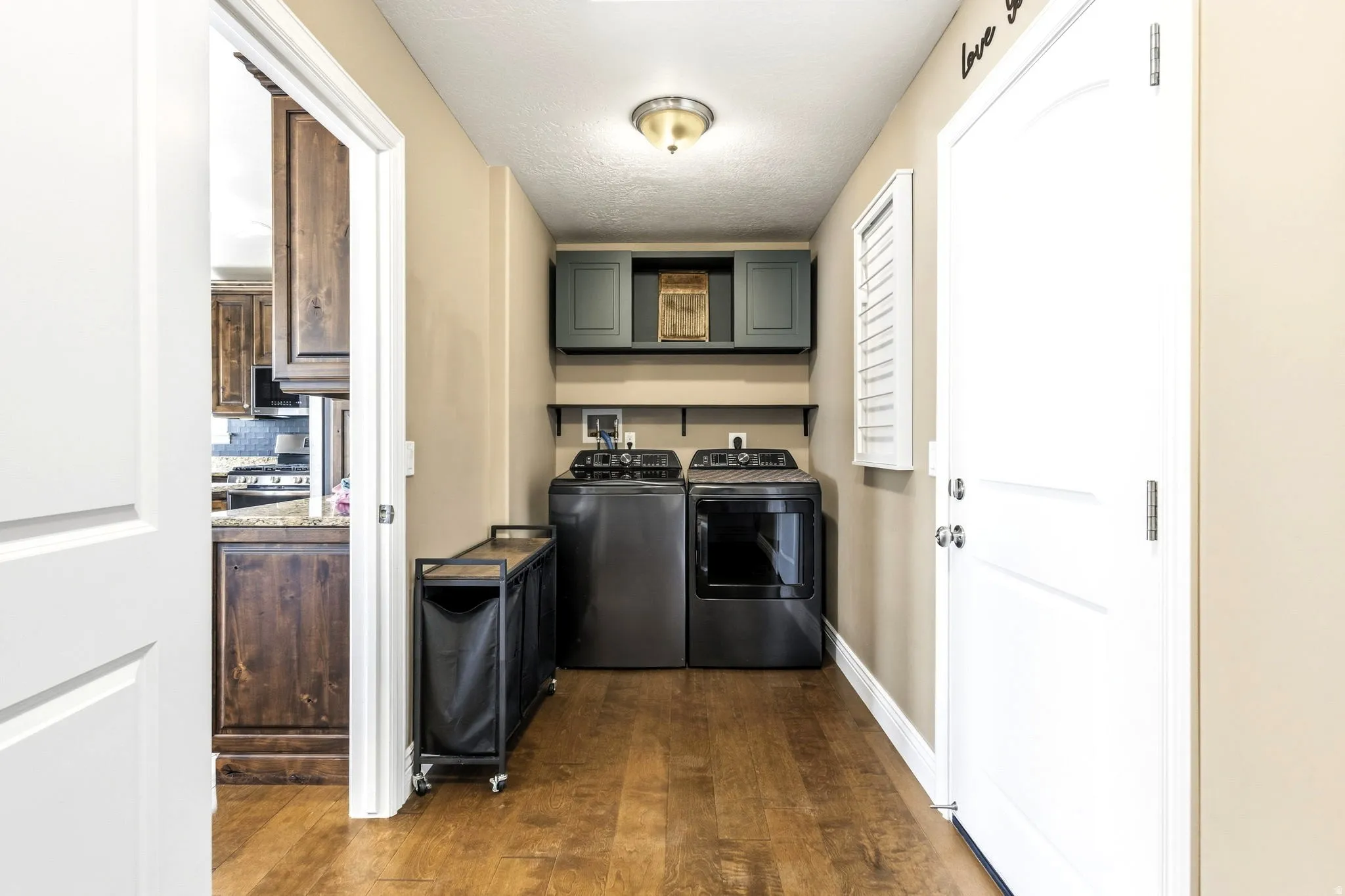 Wood-finish flooring with neutral wall paint, cabinets, washer & dryer.