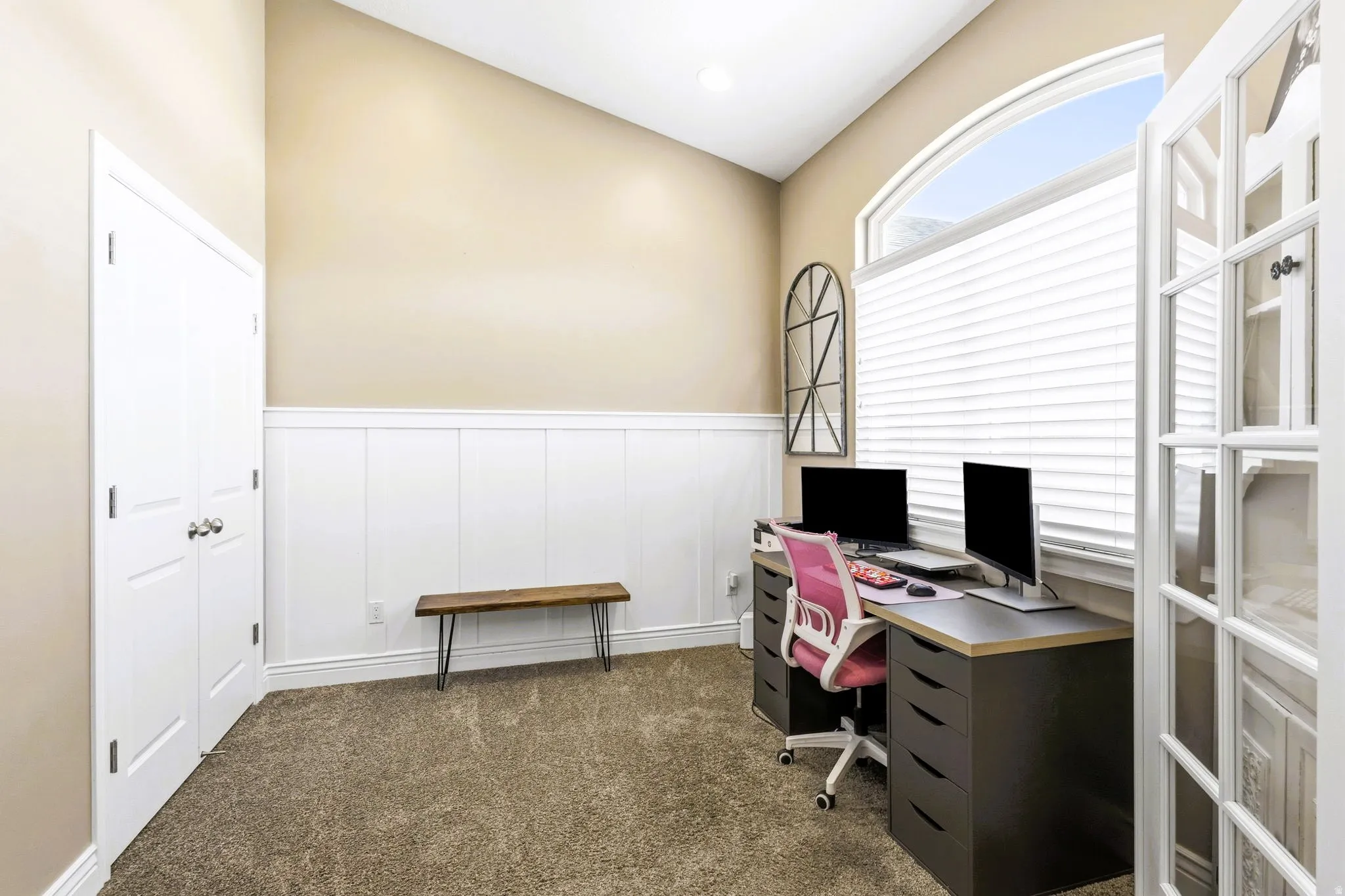 Vaulted ceiling, arched window, French doors, wainscoting, and carpet flooring, could be a potential fourth bedroom.