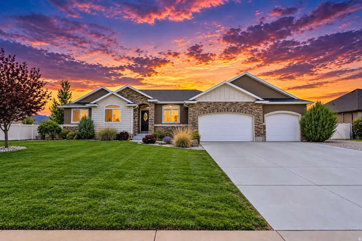 Stone and stucco exterior with multiple gables, 3 car garage and concrete driveway