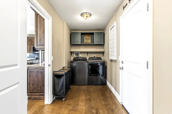 Wood-finish flooring with neutral wall paint, cabinets, washer & dryer.