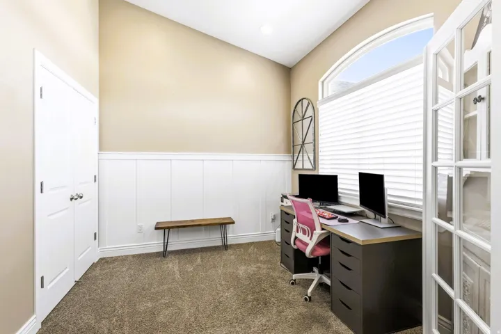 Vaulted ceiling, arched window, French doors, wainscoting, and carpet flooring, could be a potential fourth bedroom.
