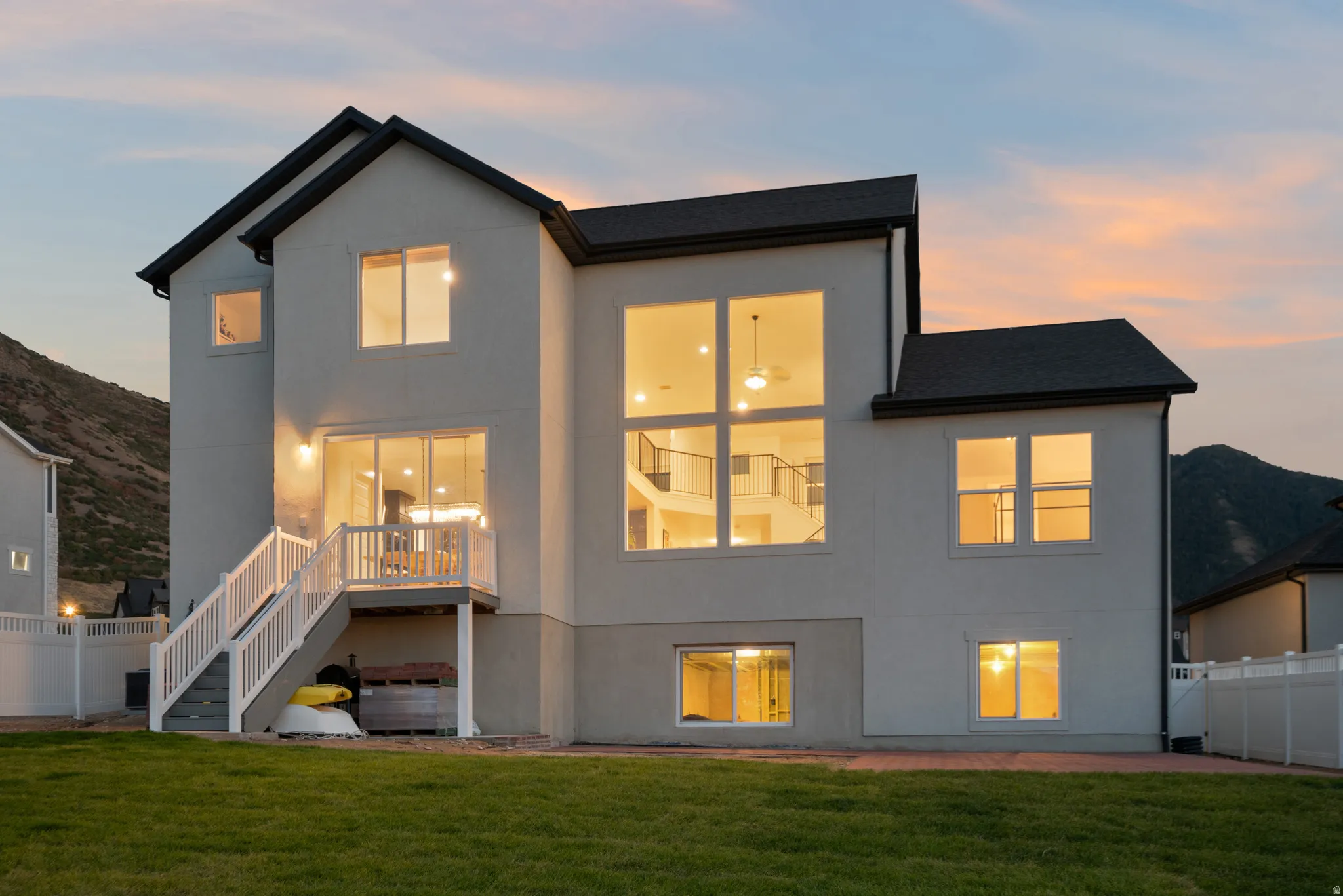 Contemporary exterior with multiple large windows, a two-story window array, and a raised composite deck with white railings