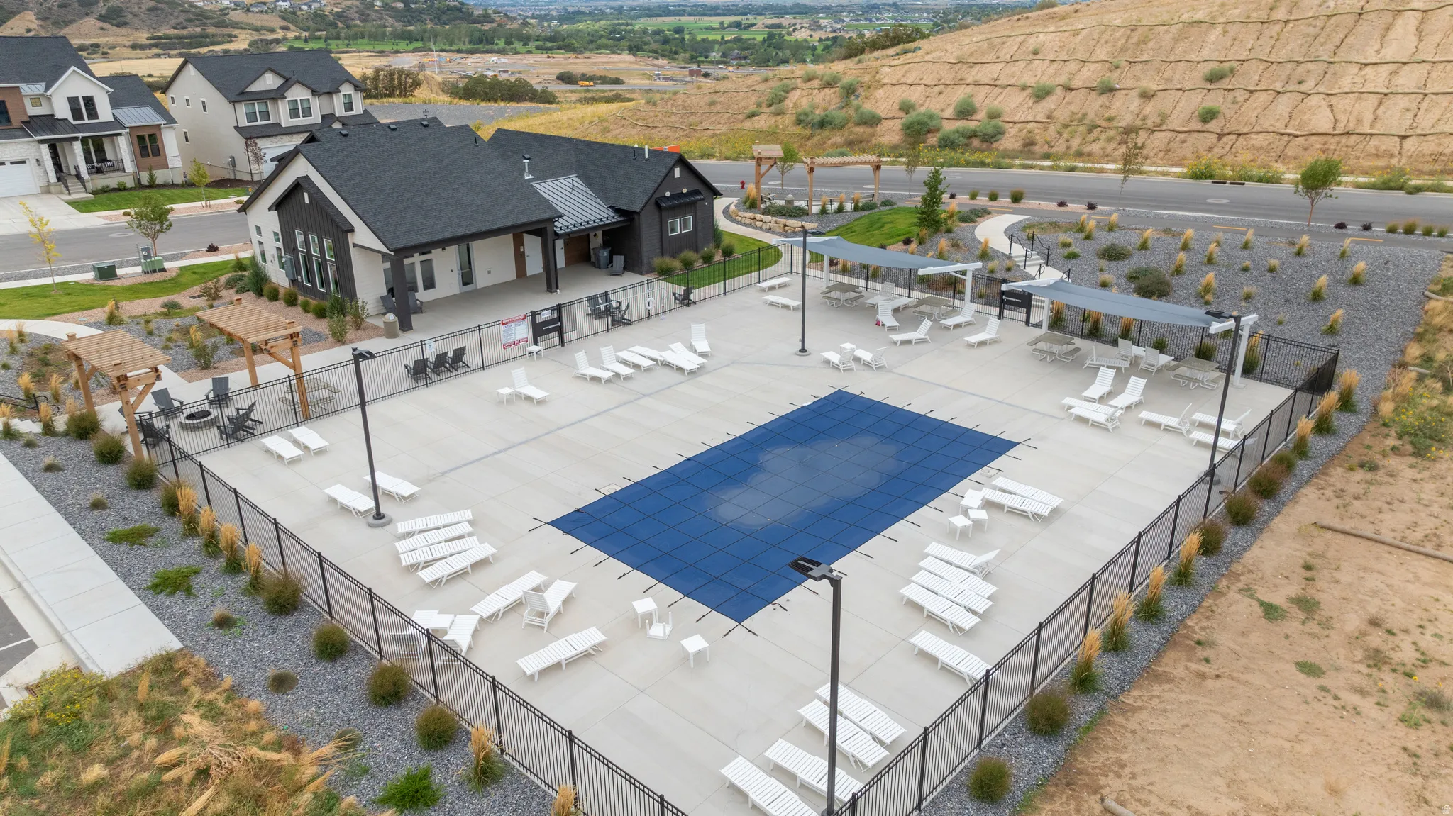 Outdoor swimming pool with a covered pool deck, adjacent amenity building, and established landscaping