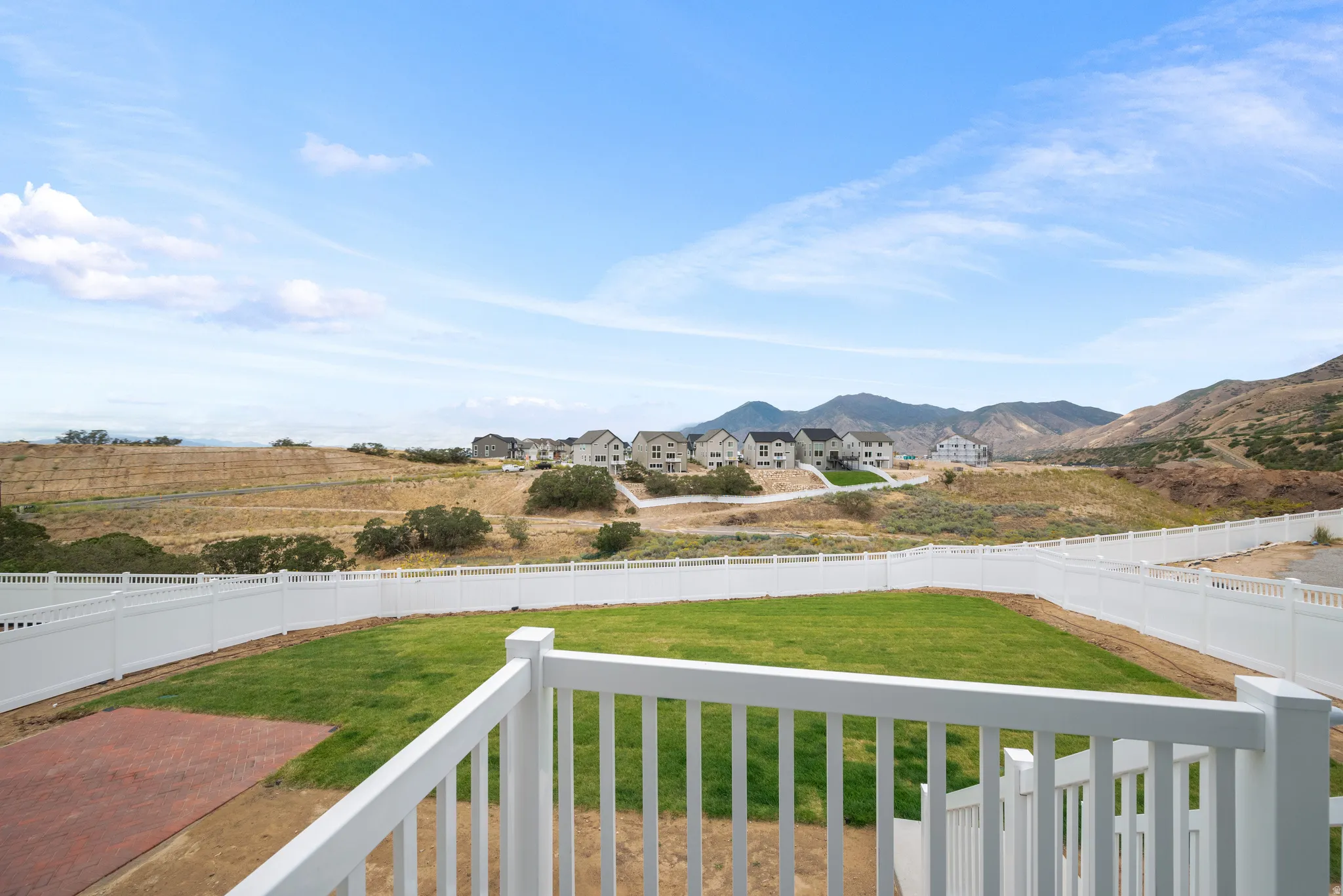 Fenced backyard with a grass lawn and a paved patio area