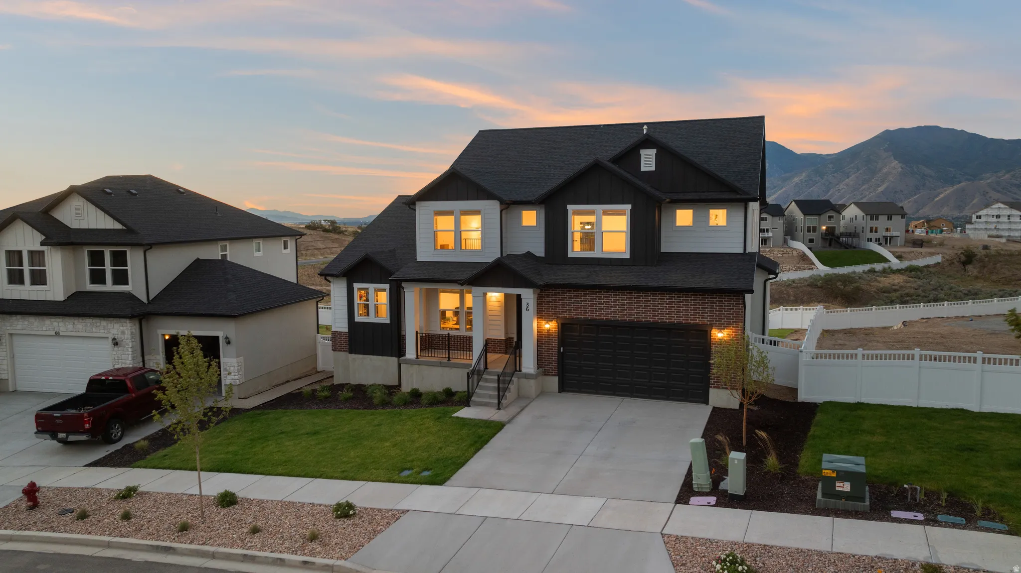 Two-story residence featuring a dark shingle roof, light-colored siding, dark brick accents, and a front-facing garage with a dark door