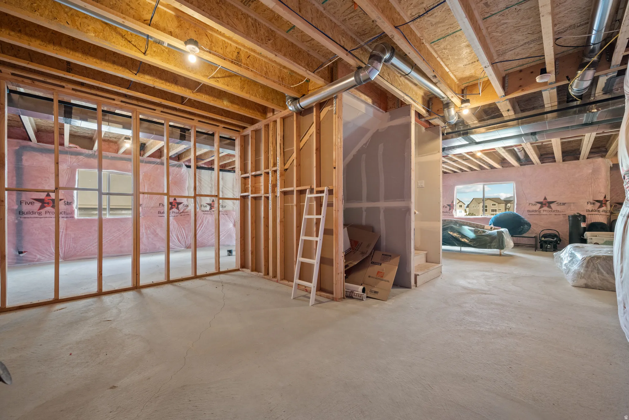 Unfinished basement space featuring exposed wood framing, concrete flooring, and visible ductwork